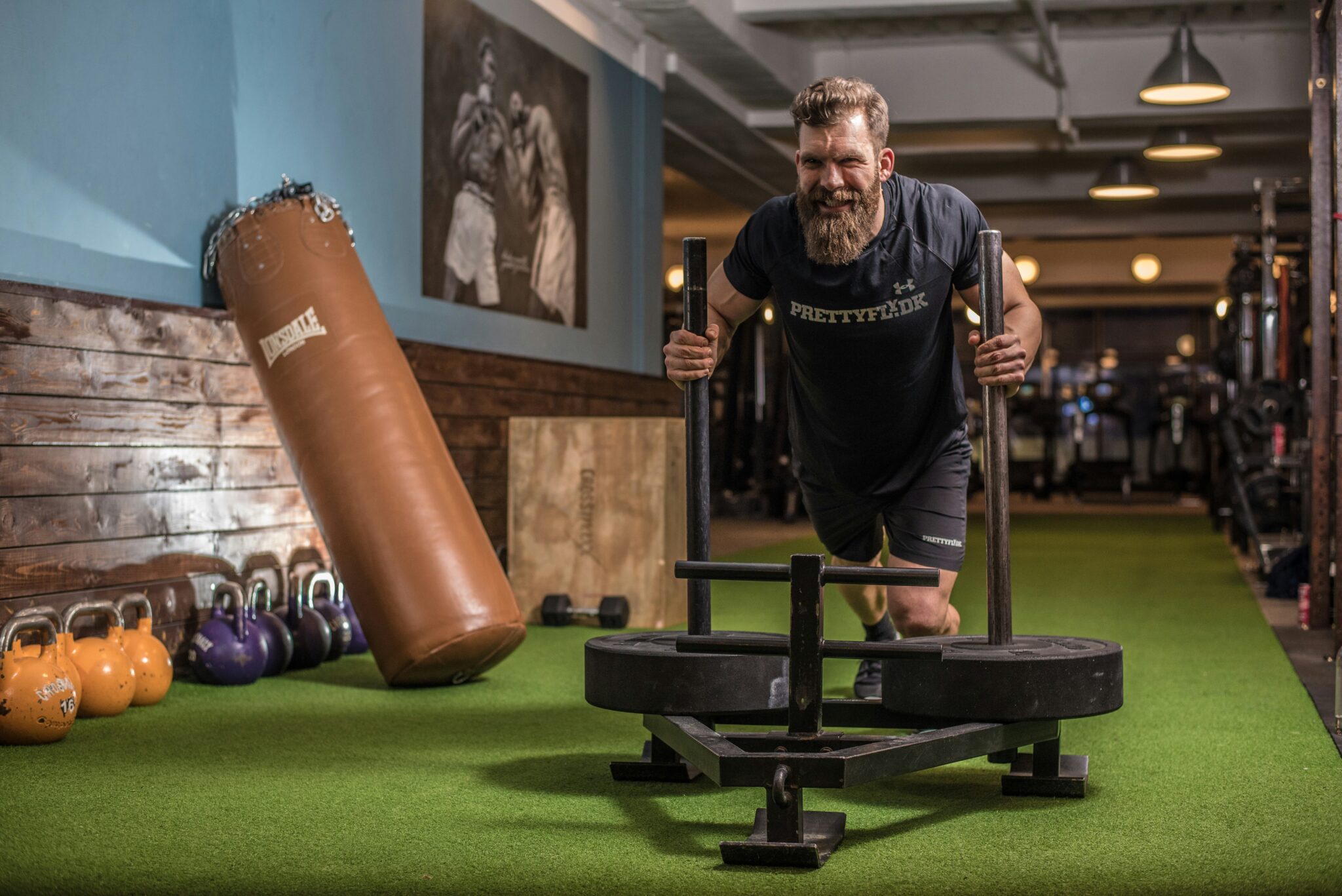Weighted sled pushed along one of a club's gym turf lanes