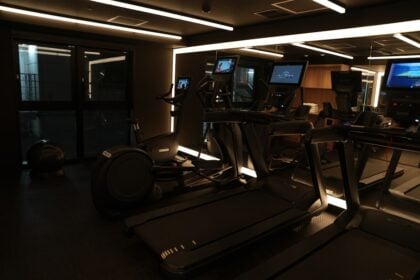 Console screens on a dark cardio floor where gym equipment firmware updates run overnight