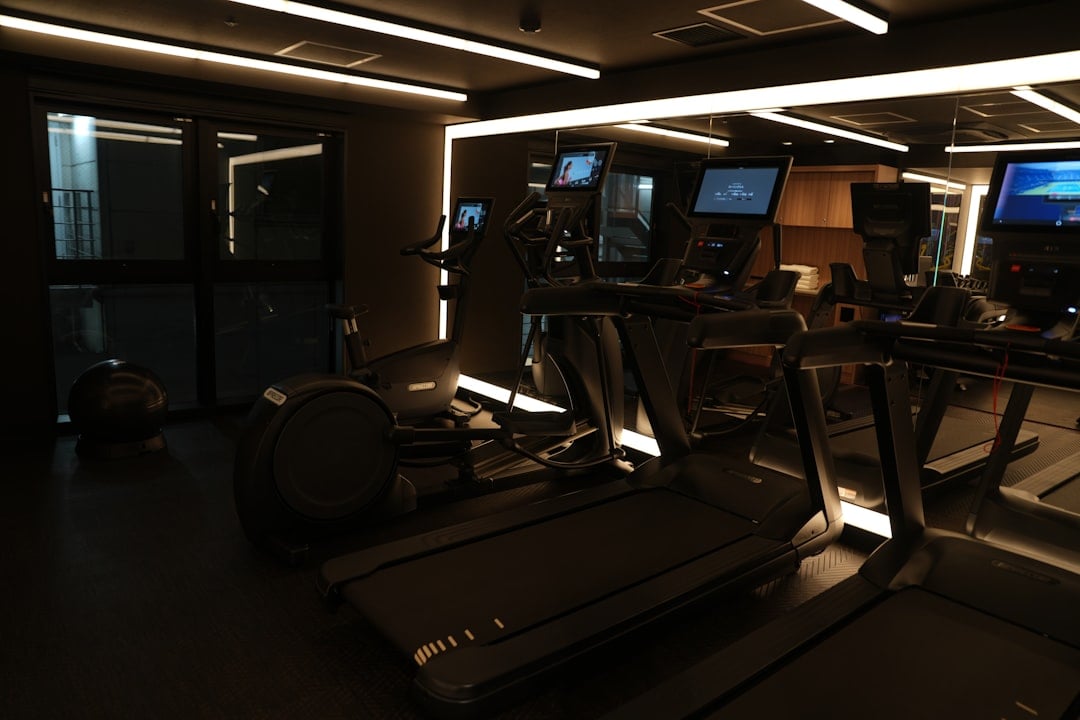 Console screens on a dark cardio floor where gym equipment firmware updates run overnight