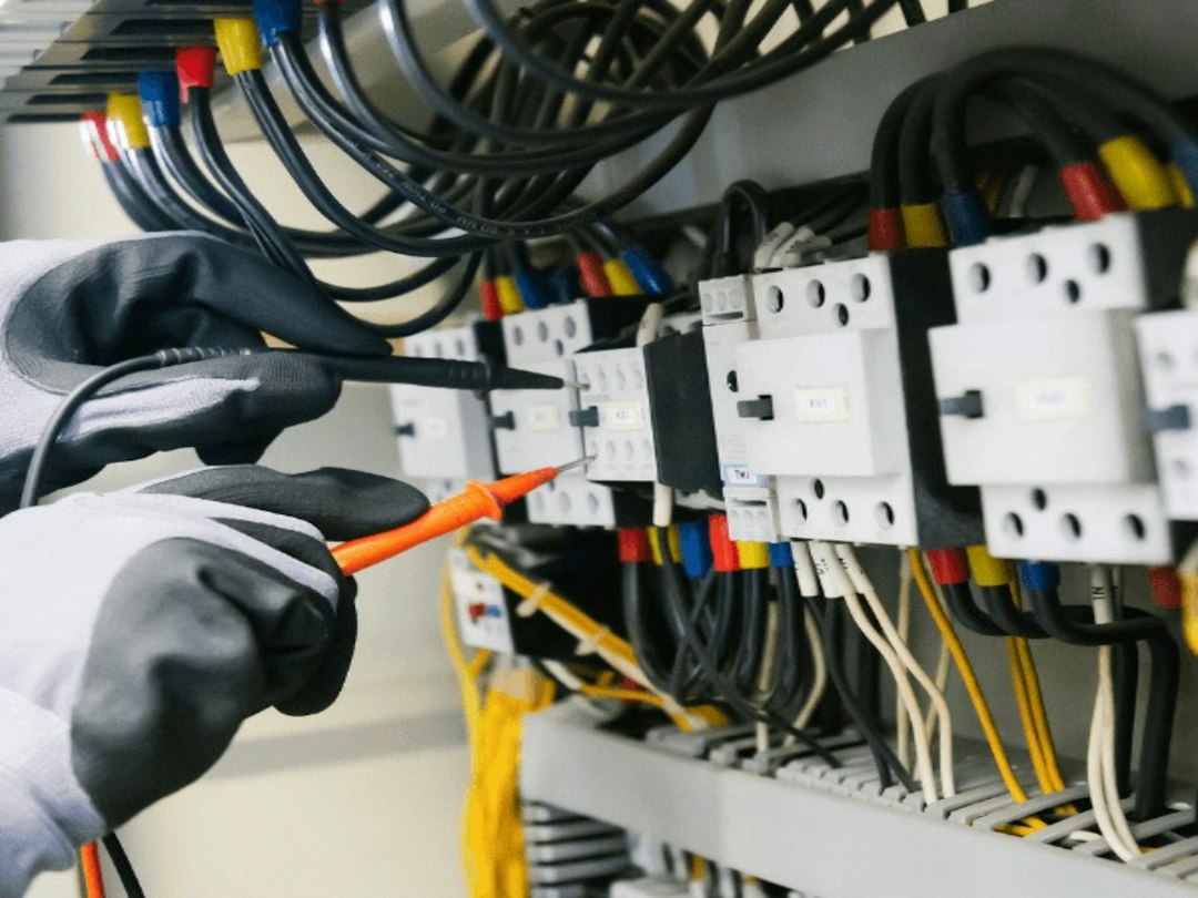 An electrician at a panel, where the savings claimed for energy-generating cardio equipment are confirmed or lost