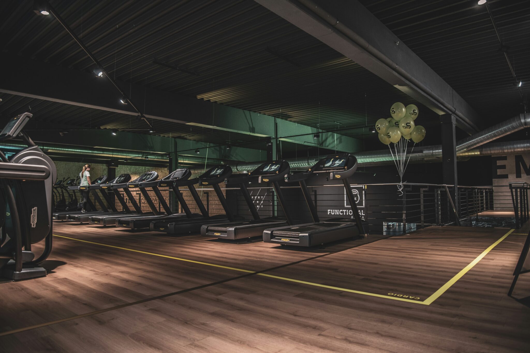 A row of treadmills on a club cardio deck where self-powered cardio equipment is now specified alongside motorized units