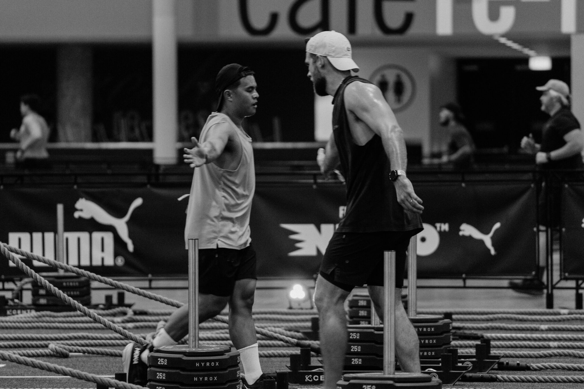 Two people pushing sleds on a turf lane, the core of any hybrid race training equipment package