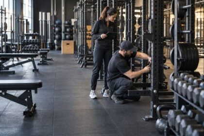 Operations team inspecting free weights and racks on a durable commercial gym floor